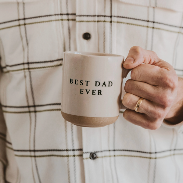 Man in plaid shirt holding ceramic coffee mug with "Best Dad Ever" text, perfect Father’s Day gift idea.