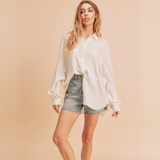 Woman wearing white oversized button down shirt from the back with raw edge hem details.