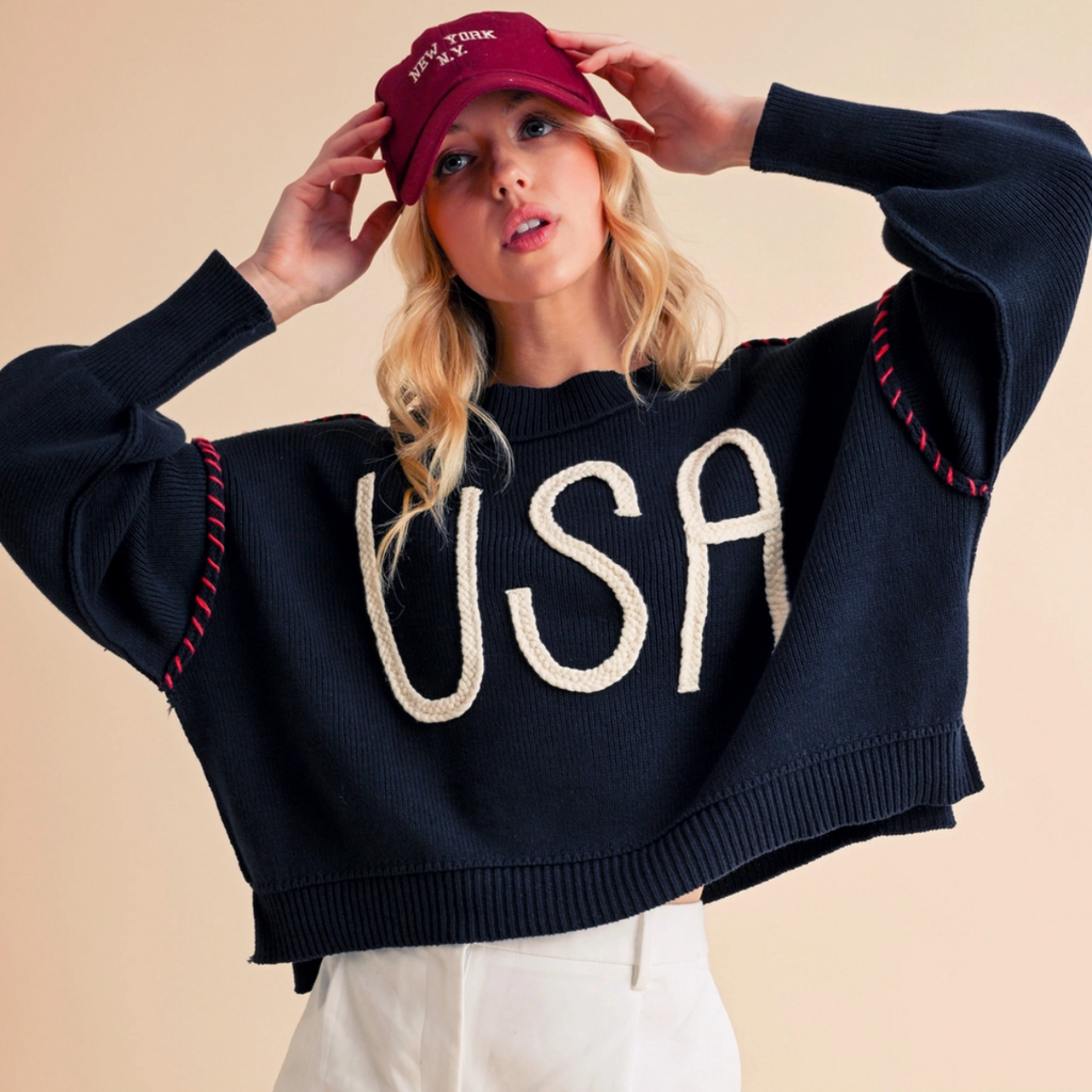 Full look of model styling the navy USA sweater with casual white shorts