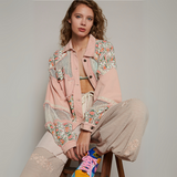 Model wearing a vintage-inspired pink patchwork mesh jacket with floral prints and lace accents, paired with relaxed-fit pants.
