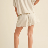 Back view of beige linen shorts with relaxed fit and subtle hem curve.