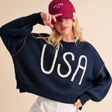 Front view of woman wearing USA sweater with red cap and bold embroidered lettering