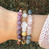 Woman wearing a stack of beaded bracelets, including the rose quartz and labradorite Agape Divine Love Bracelet.