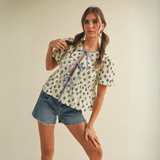 Cream peplum blouse with navy floral print and tie-front closure worn by female model in studio setting.