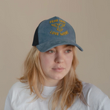 Woman wearing blue corduroy trucker hat with “Fear Less Love More” embroidered in yellow and a dove graphic.