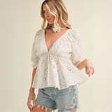 Side view of white peplum blouse with eyelet embroidery and flowy silhouette