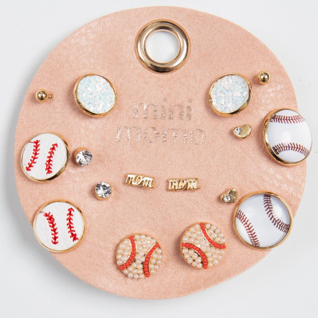 Mini Momo Baseball Earring Set featuring baseball-themed gold-tone, pearl, and enamel stud earrings displayed on a tan round leather card