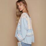 Side profile of a model wearing a flowy, lace-detailed boho blouse with long sleeves and a back zipper.