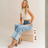 Model sitting wearing High Waist Wide Leg Cuffed Jeans with white crop top and tan boots