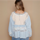 Back view of a boho-style blouse showcasing the lace and floral embroidery with a zippered closure.