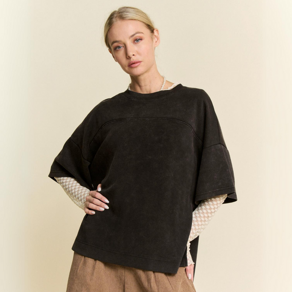 Model wearing a washed fabric crew neck top with dropped dolman sleeves, paired with neutral-toned bottoms against a light beige background.