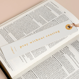 "Elegant cream scripture bookmark reading 'Pray without ceasing' placed in open Bible."