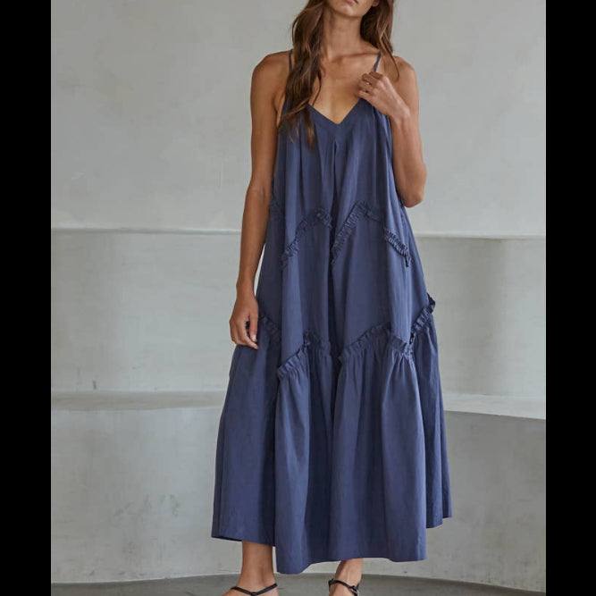 Woman wearing a blue dress standing against a plain background