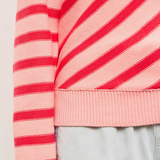 Close-up of the Cross Stripe V Neck Sweater Top, highlighting the diagonal stripe detail and soft knit texture in pink and red.