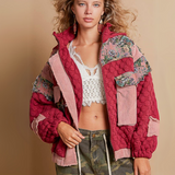 Model wearing an oversized floral quilted jacket with patchwork details and textured fabric, styled with camo pants and lace accents.