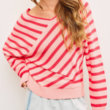 Model wearing the Cross Stripe V Neck Sweater Top, showcasing the flattering V-neckline and relaxed fit in pink and red stripes.