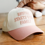 Side view of the "Revival Starts With Family" hat placed on a wooden table, highlighting its pastel tones and bold lettering.