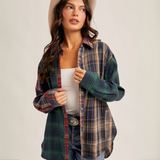"Front view of woman wearing oversized mixed plaid flannel shirt with red, green, and navy tones"

