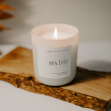 Product photo of lit Spa Day soy candle with label reading “Sea Salt / Jasmine / Wood / Cream”

