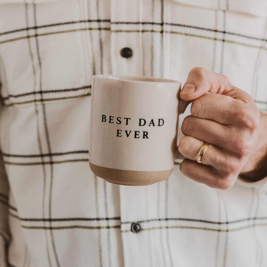 Man in plaid shirt holding ceramic coffee mug with "Best Dad Ever" text, perfect Father’s Day gift idea.


