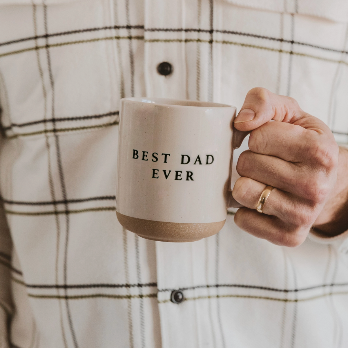Man in plaid shirt holding ceramic coffee mug with "Best Dad Ever" text, perfect Father’s Day gift idea.

