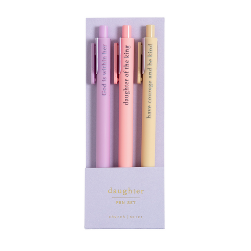 Faith-based pens writing spiritual phrases in ink, laid out on a flat-lay with a notepad.

