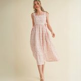 Woman wearing pink floral ruffle strap midi dress with side bows and tiered skirt

