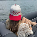 Woman wearing red and white America EST. 1776 hat while sitting on a boat

