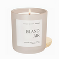 A lit Island Air candle in a white frosted glass jar with minimalist label, placed on a white background.