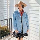  Woman wearing the embroidered denim jacket, styled with a hat and dress for a casual-chic look.