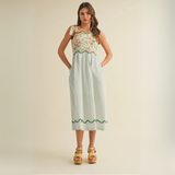 Front view of model wearing floral and striped patchwork midi dress with tie shoulder straps and pockets
