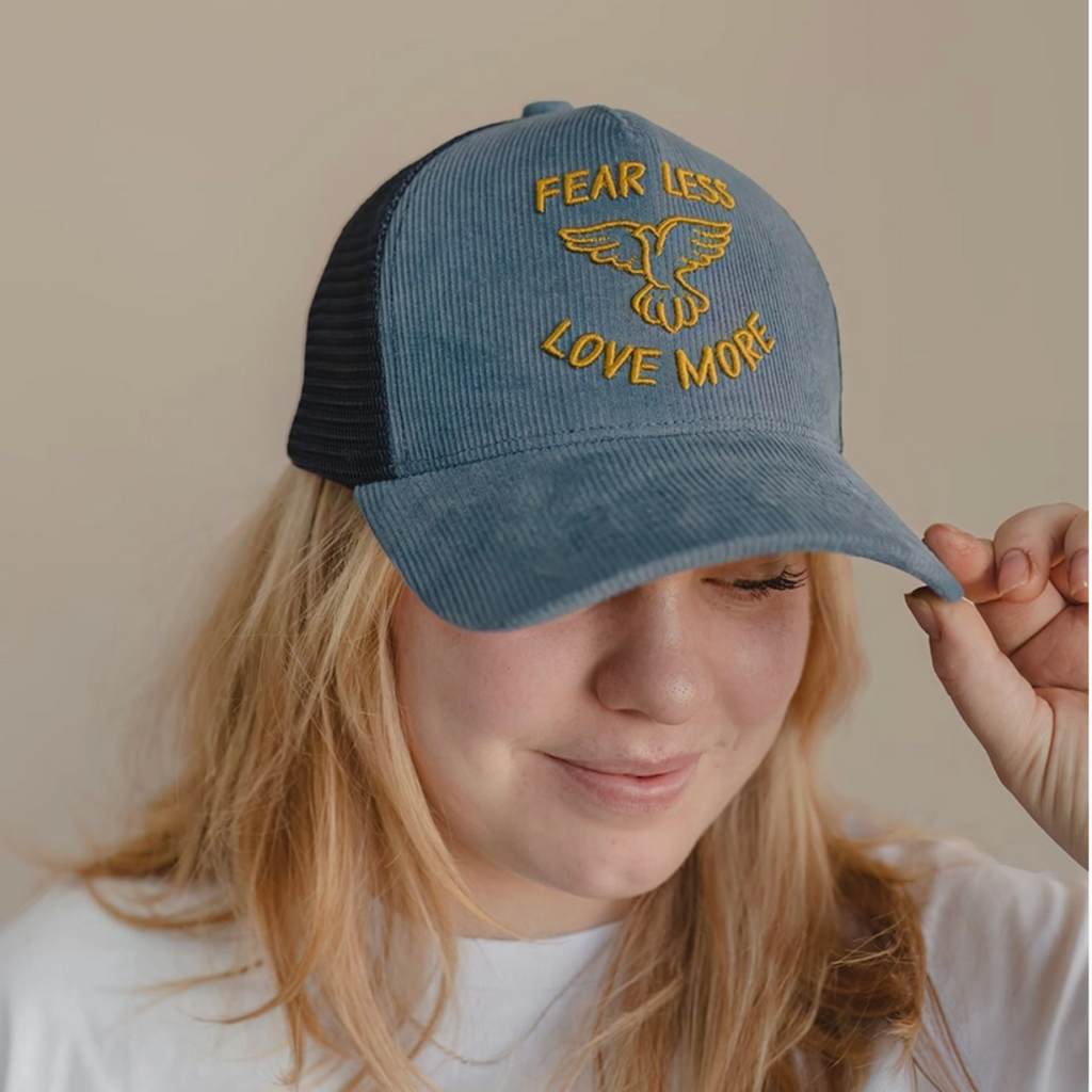  Front view of woman modeling positive message trucker hat with mesh back and curved brim.