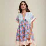 Woman wearing a floral babydoll dress with a V-neckline, soft ruffle hem, and patchwork print.