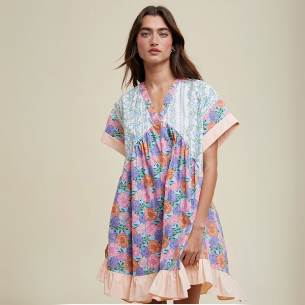 Woman wearing a floral babydoll dress with a V-neckline, soft ruffle hem, and patchwork print.