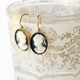 Close-up of small black cameo earrings with intricate detailing.
