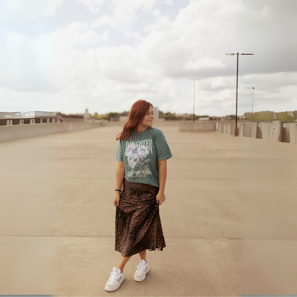 Woman wearing the Daughter of the King graphic tee, standing in an outdoor urban setting.