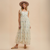 Woman wearing ivory floral maxi dress with shoulder ties and a wide-brim hat

