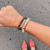 Stack of mixed-material bracelets on a wrist, including the Blue Lace Agate & Jasper Beaded Bracelet styled with other pieces.