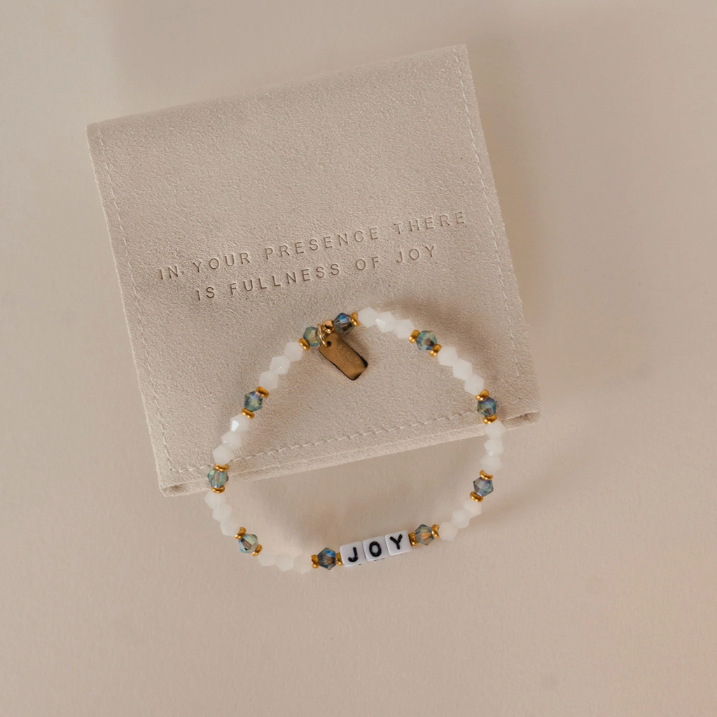 Bracelet with 'JOY' beads on a textured card with engraved text