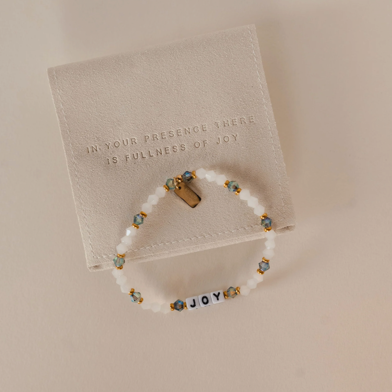Bracelet with 'JOY' beads on a textured card with engraved text