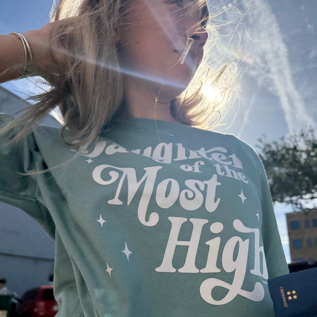 Person wearing a green shirt with text on the back, standing outdoors.