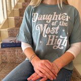 Person wearing a t-shirt with 'Daughter of the Most High' text, sitting on a staircase.