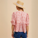 Back view of the Bow Accent Floral Top showcasing its flowing peplum design and puff sleeves in a crinkle-textured floral fabric.