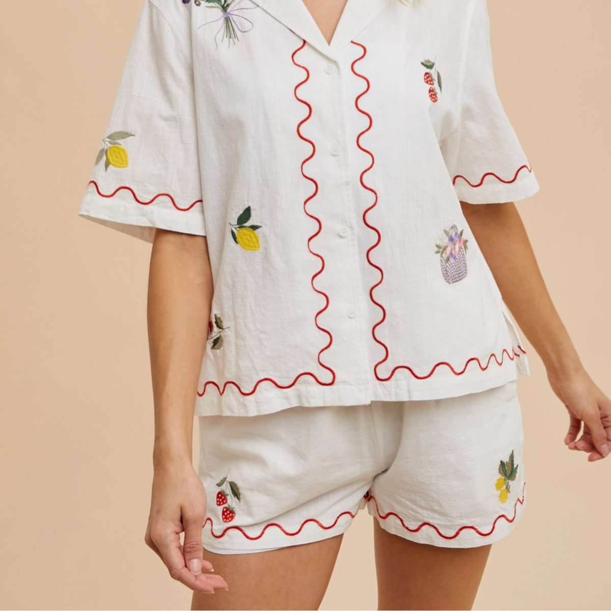 Front view of embroidered lounge shorts with red trim and strawberry details

