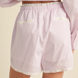 Back view of pink striped shorts featuring floral-trimmed pockets and waistband.

