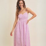 Smiling model wearing lilac floral dress, showing its flowy silhouette.
