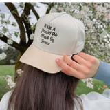 Woman adjusting the faith-based embroidered hat in a natural outdoor setting.