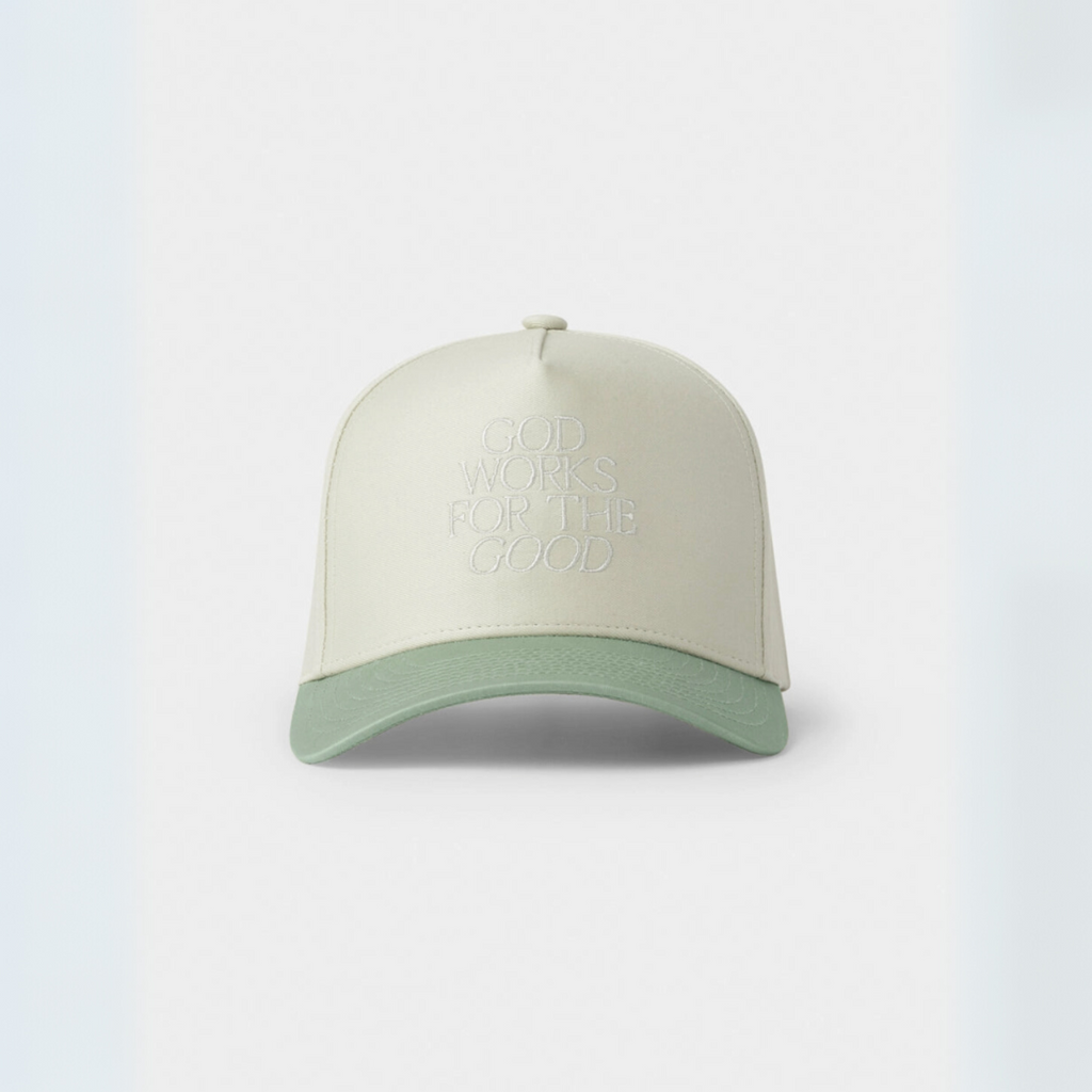 "Cream and sage green trucker hat with 'God Works for the Good' embroidered on the front panel."

