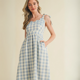 Close-up of gingham dress bodice with blue floral embroidery and scalloped edge


