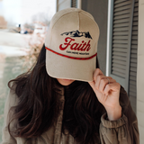 "Close-up of a woman adjusting her faith-based corduroy trucker hat with embroidered mountain design and bold lettering."

